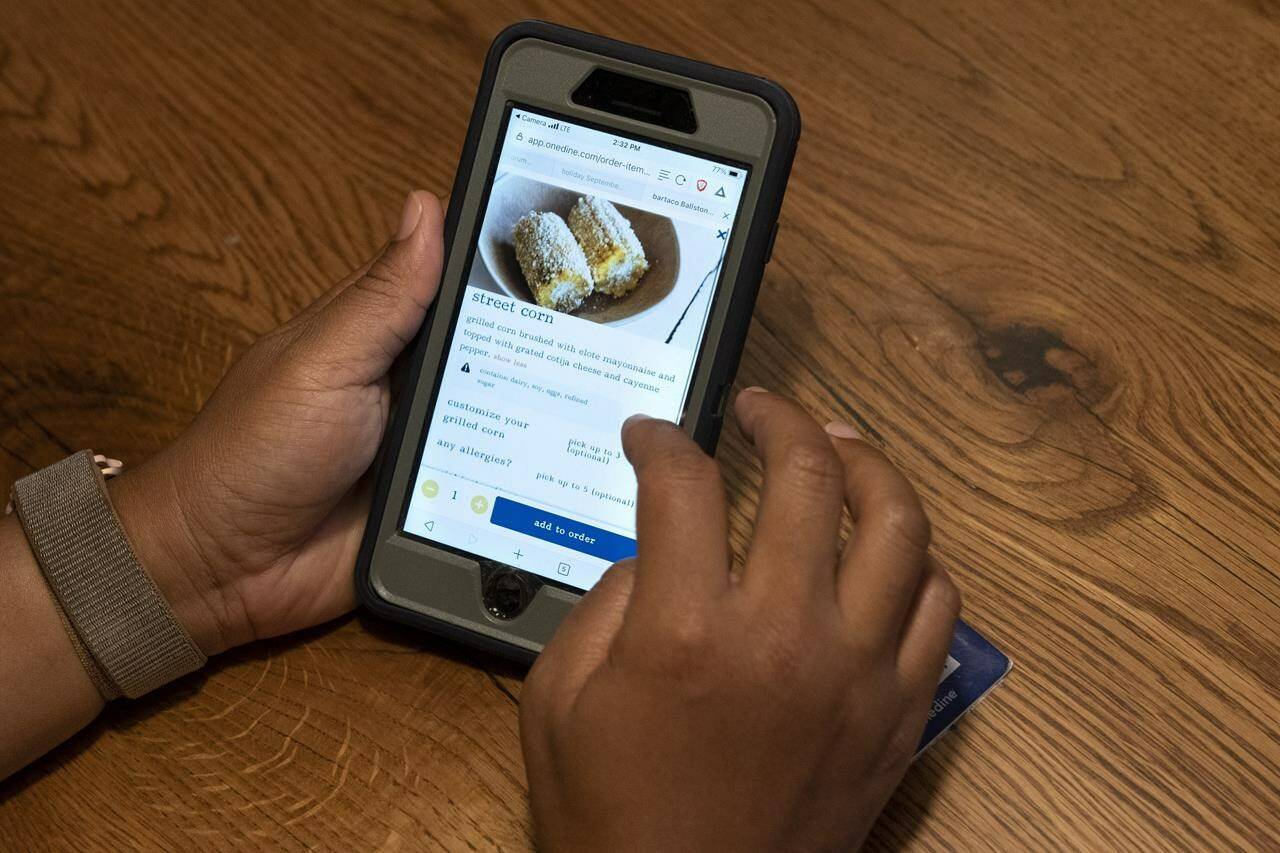 A diner at Bartaco uses their app to order an item off the menu, at the restaurant in Arlington, Va., on Thursday, Sept. 2, 2021. The restaurant is using an automated app for ordering and payments. Instead of servers they use “food runners” to get the food to the tables. (AP Photo/Jacquelyn Martin)