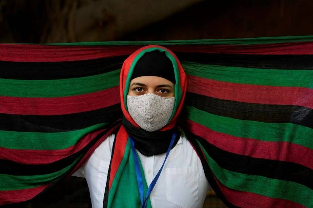 FILE - In this Aug. 23, 2021, file photo, an Afghan refugee living in India wearing a scarf in the colors of Afghanistan flag participates in a protest against the Taliban takeover of Afghanistan outside the office of United Nation High Commissioner for Refugees, in New Delhi, India. India’s leaders are anxiously watching the Taliban takeover in Afghanistan, fearing that it will benefit their bitter rival Pakistan and feed a long-simmering insurgency in the disputed region of Kashmir, where militants already have a foothold. (AP Photo/Manish Swarup, File)