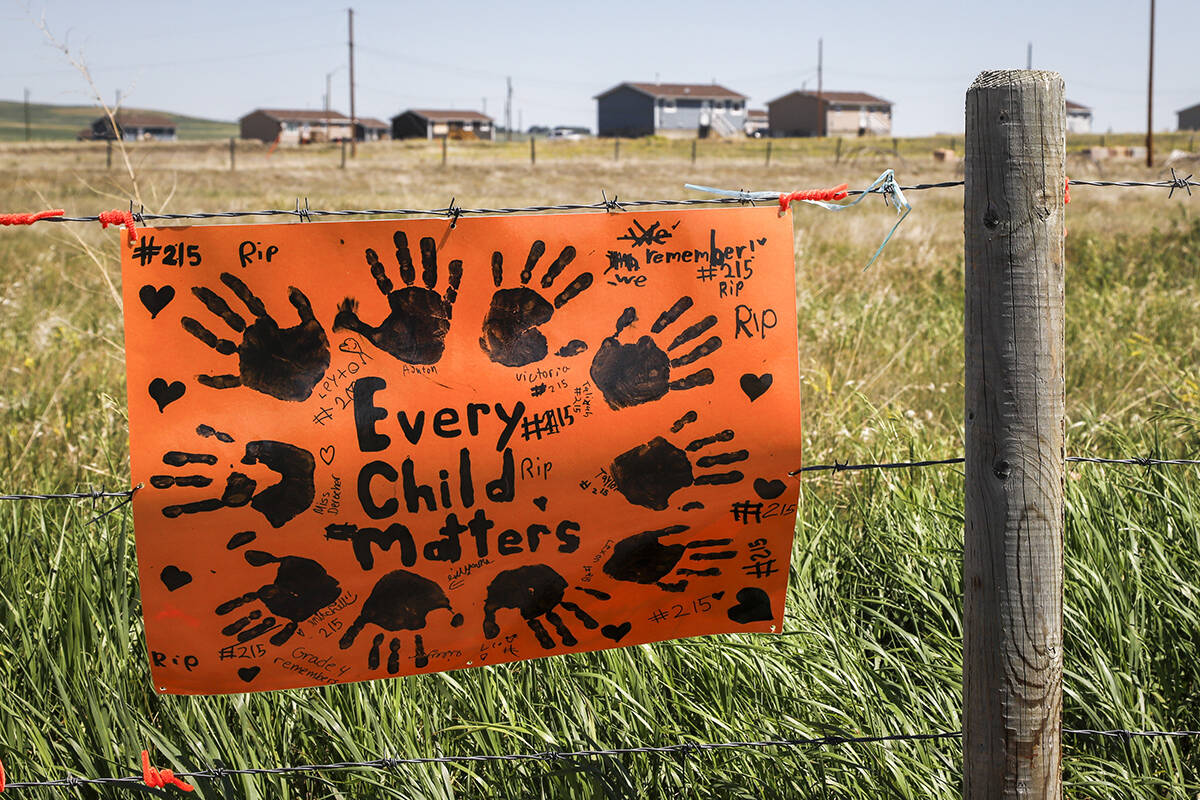 A sign commemorating victims of residential schools is attached to a fence line in front of homes on the Siksika First Nation, east of Calgary near Gliechen, Alta., Tuesday, June 29, 2021. THE CANADIAN PRESS/Jeff McIntosh