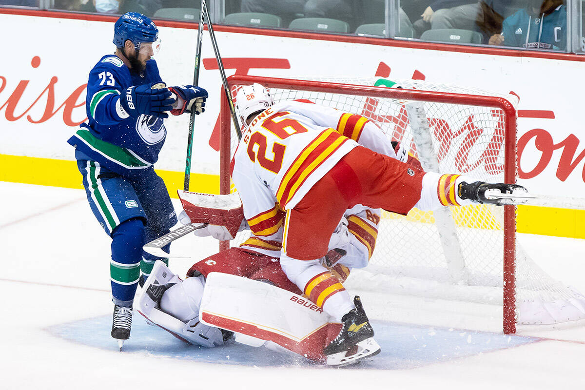 Calgary Flames’ Michael Stone (26) collides with teammate, goalie Daniel Vladar, of the Czech Republic, as Vancouver Canucks’ Justin Dowling, left, watches during the second period of a pre-season NHL hockey game in Abbotsford on Monday, Sept. 27, 2021. THE CANADIAN PRESS/Darryl Dyck