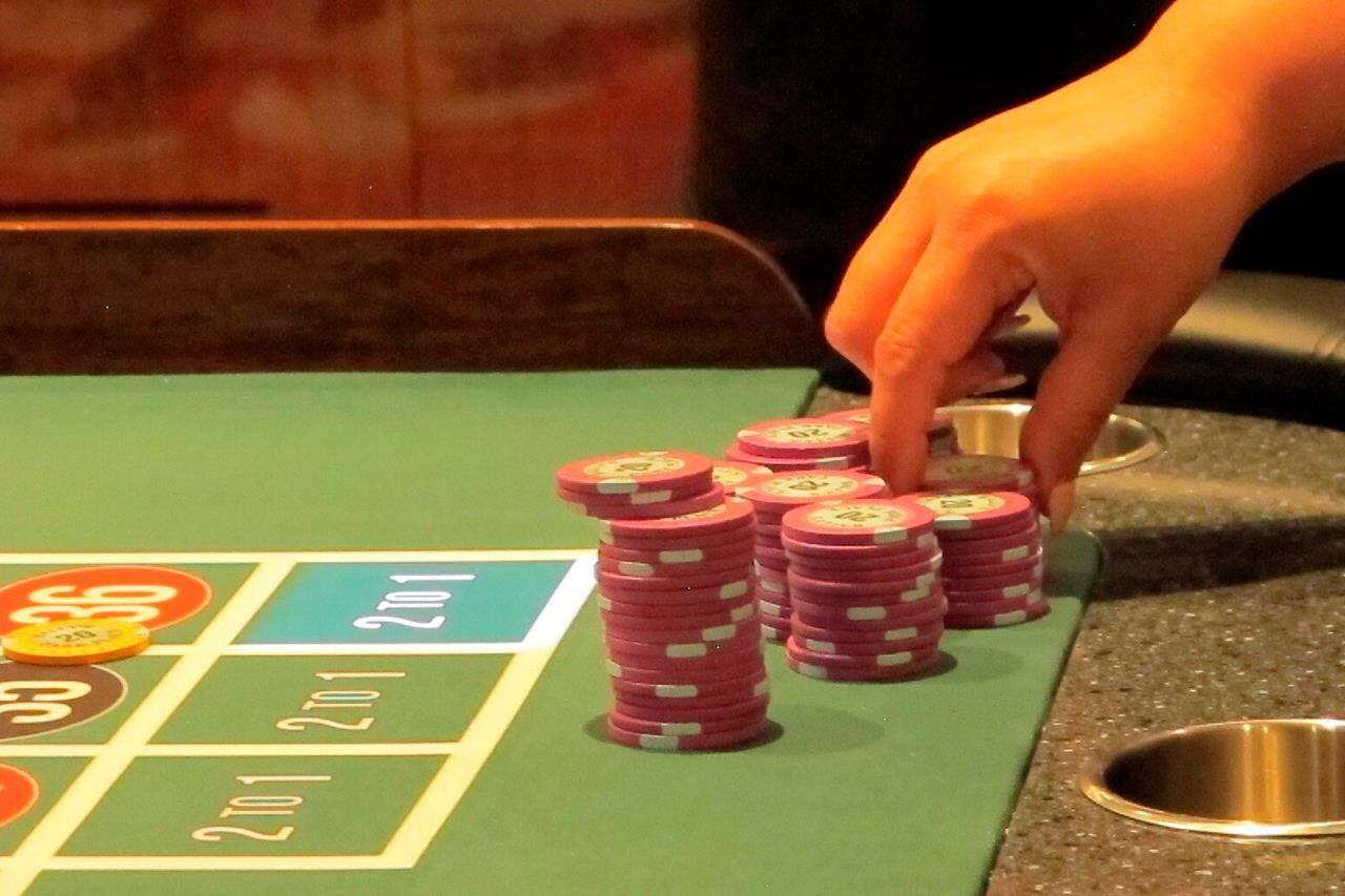 In this June 23, 2021 photo a gambler picks up chips at a roulette table at Bally's casino in Atlantic City N.J. Lawyers representing operators of British Columbia's largest gaming companies say compliance with provincial regulations to combat money laundering is and always has been a top priority at provincial casinos.THE CANADIAN PRESS/AP/Wayne Parry