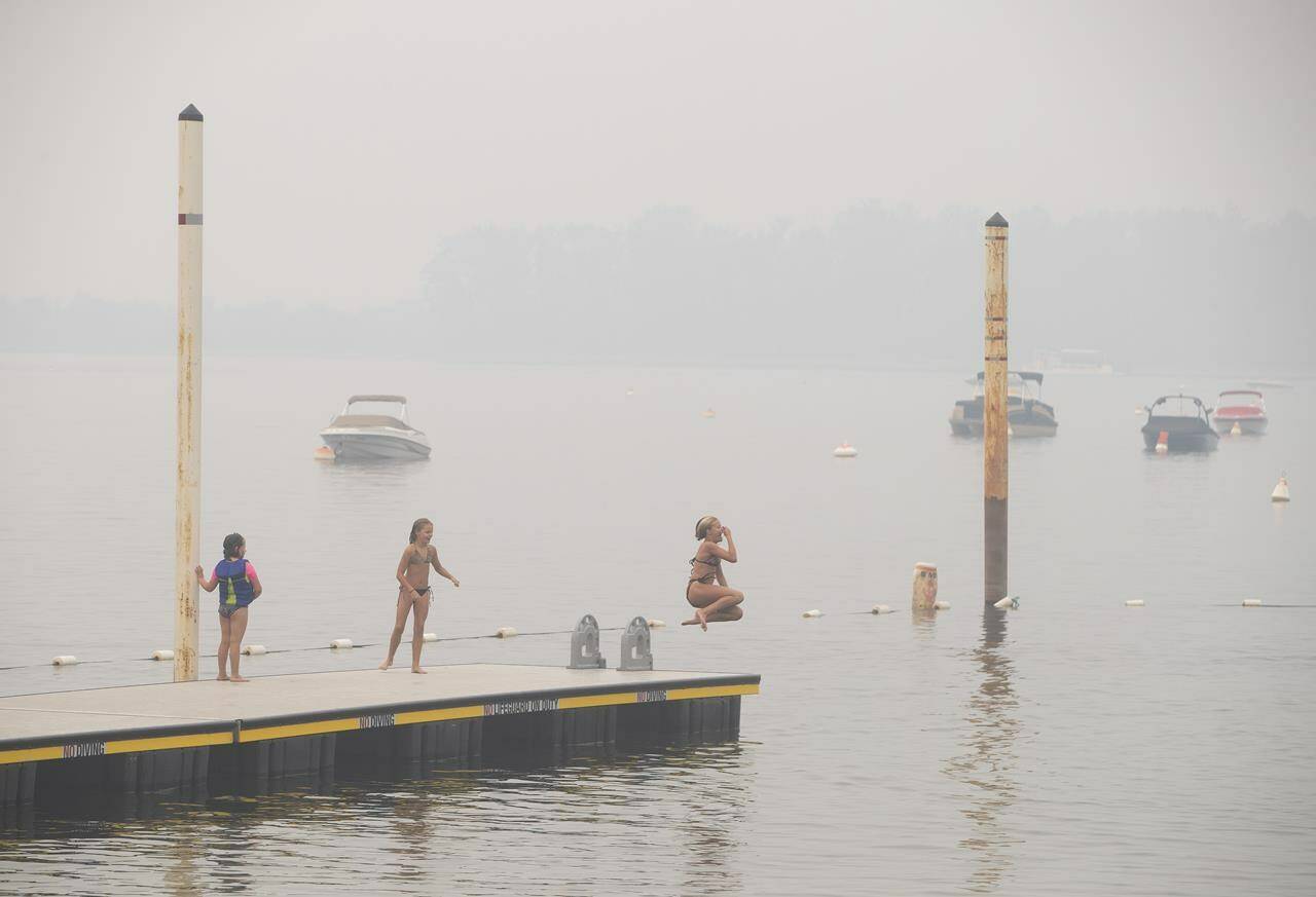 Wildfire smoke fills the air and obstructs the view of the mountains as people continue to take part in outdoor activities in Sicamous B.C., on Thursday July 29, 2021. British Columbia is gearing up to respond to another heat wave by taking several steps including opening civic centres that would otherwise be closed so people can escape to a cool place if they lack air conditioning. THE CANADIAN PRESS/Jason Franson