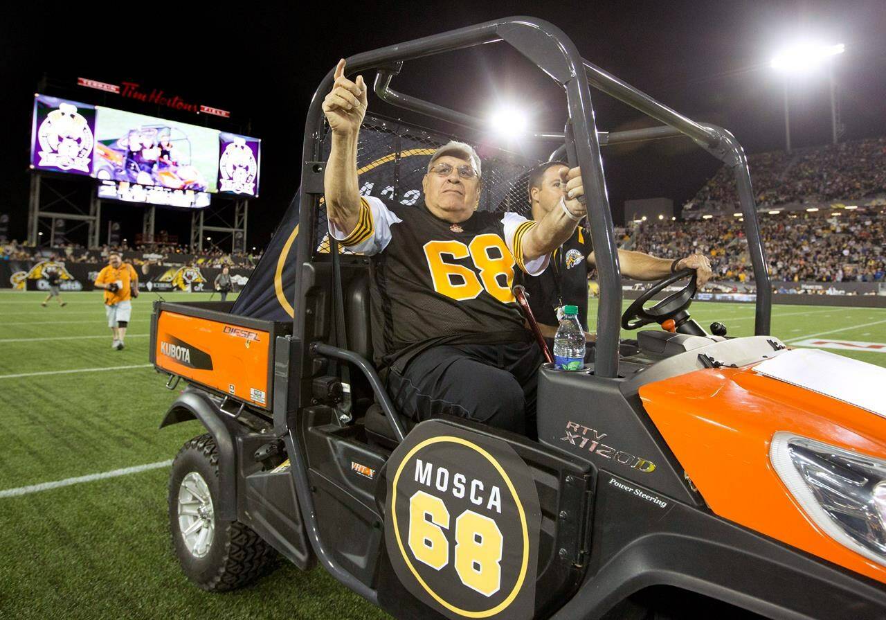 FILE - Hamilton Tiger-Cats alumnus Angelo Mosca is driven out onto the field in Hamilton, Ontario, Thursday, Aug. 27, 2015. Mosca, the five-time Grey Cup champion defensive lineman best remembered for a controversial hit and a subsequent fight with Joe Kapp 40 years later, died Saturday, Nov. 6, 2021. He was 84. (Peter Power/The Canadian Press via AP, File)