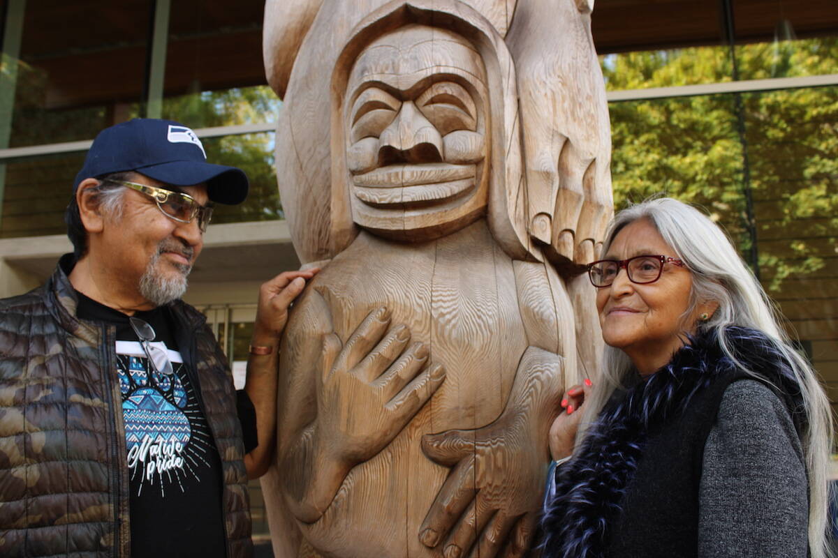 Alberni Residential School survivor Kathleen Horne, right, and her husband Doug LaFortune stand by one of LaFortune’s carvings outside the First Peoples House at the University of Victoria on Sept. 24. (Jake Romphf/News Staff)