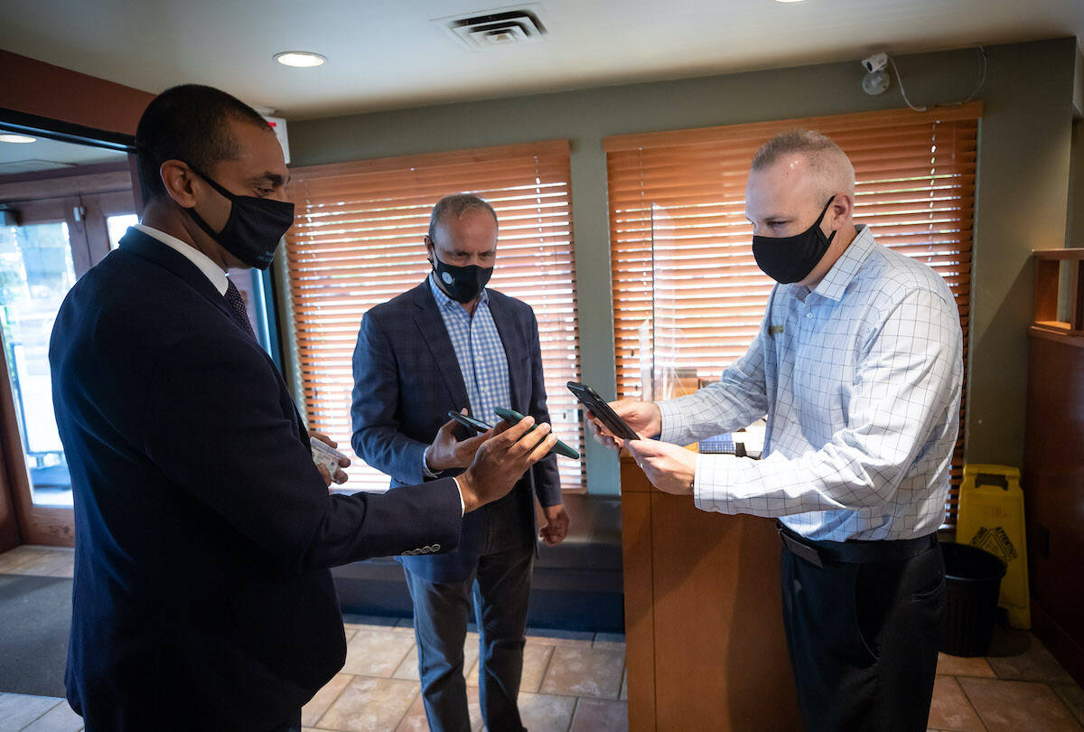 Ravi Kahlon, left, B.C. Minister of Jobs, Economic Recovery and Innovation, and Minister of Labour Harry Bains have their provincial COVID-19 vaccine cards scanned by White Spot restaurant general manager Bill Warwick, right, before having breakfast in Delta, B.C., on Wednesday, September 15, 2021. British Columbia’s COVID-19 vaccine card system went into effect Monday. Anyone who wants access to a range of non-essential indoor services must show proof of at least one dose of vaccine, with a second shot required by Oct. 24. THE CANADIAN PRESS/Darryl Dyck