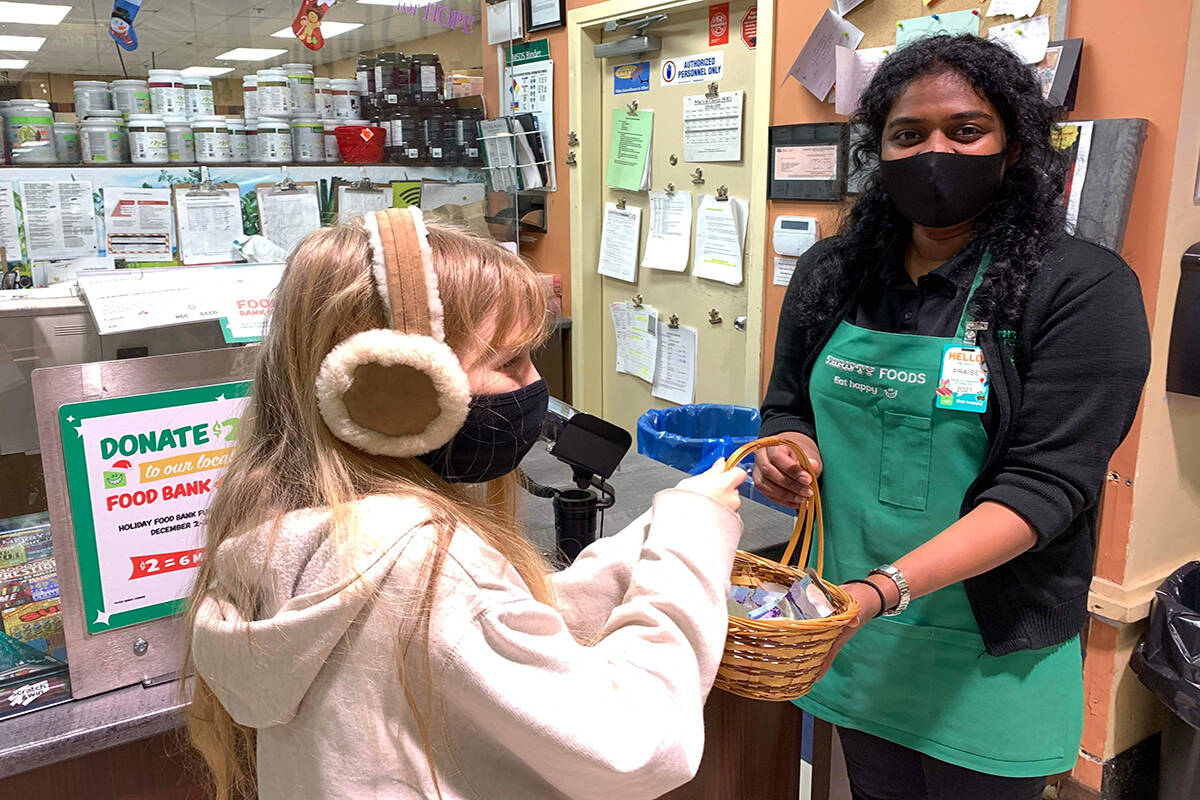 11-year-old Mimi Russow hands a basket of donations and leftover gratitude rocks to Thrifty’s employee, Praise, to go toward holiday meals for families in need. (Photo courtesy of Soren Russow)