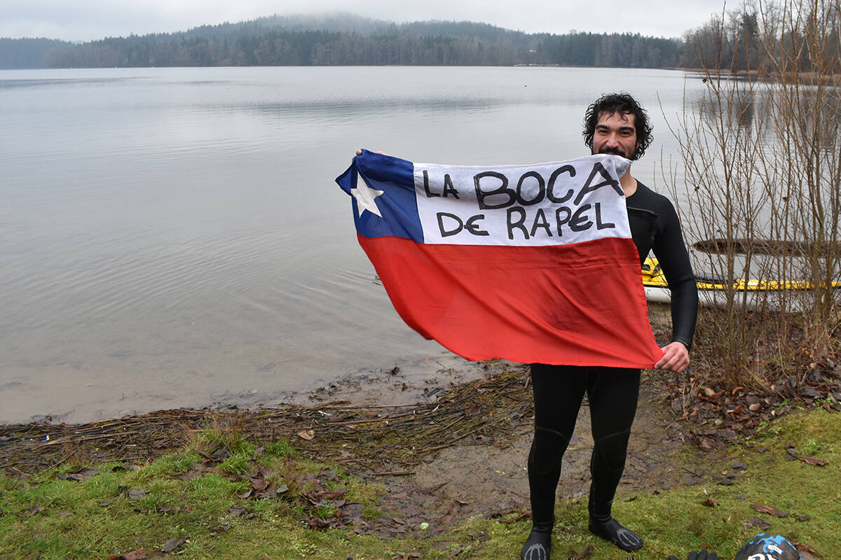 Lucas Gentina holds a Chilean flag listing the name of his hometown, La Boca de Rapel, after swimming across Elk Lake to fundraise for equipment benefiting residents at the long-term care unit of Saanich Peninsula Hospital, where he works as a rehabilitation assistant. (Wolf Depner/News Staff)