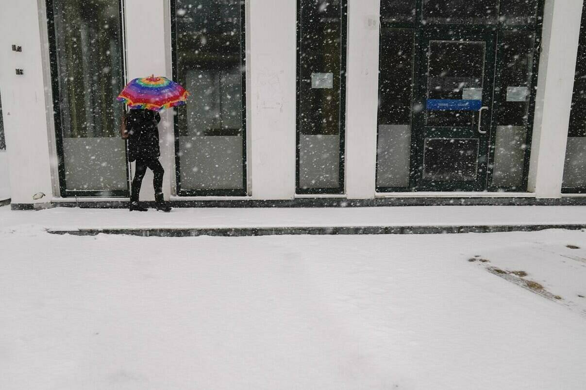 A woman with an umbrella walks during a snowfall in Agios Steganos, north of Athens, on Monday, Jan. 24, 2022. The wave of bad weather hitting Greece is forecast to continue through Tuesday, and has seen snow falling even on some islands. Authorities have warned the public to avoid all but essential outdoor movement, and several major roads and highways are passable only with snow chains. (AP Photo/Thanassis Stavrakis)