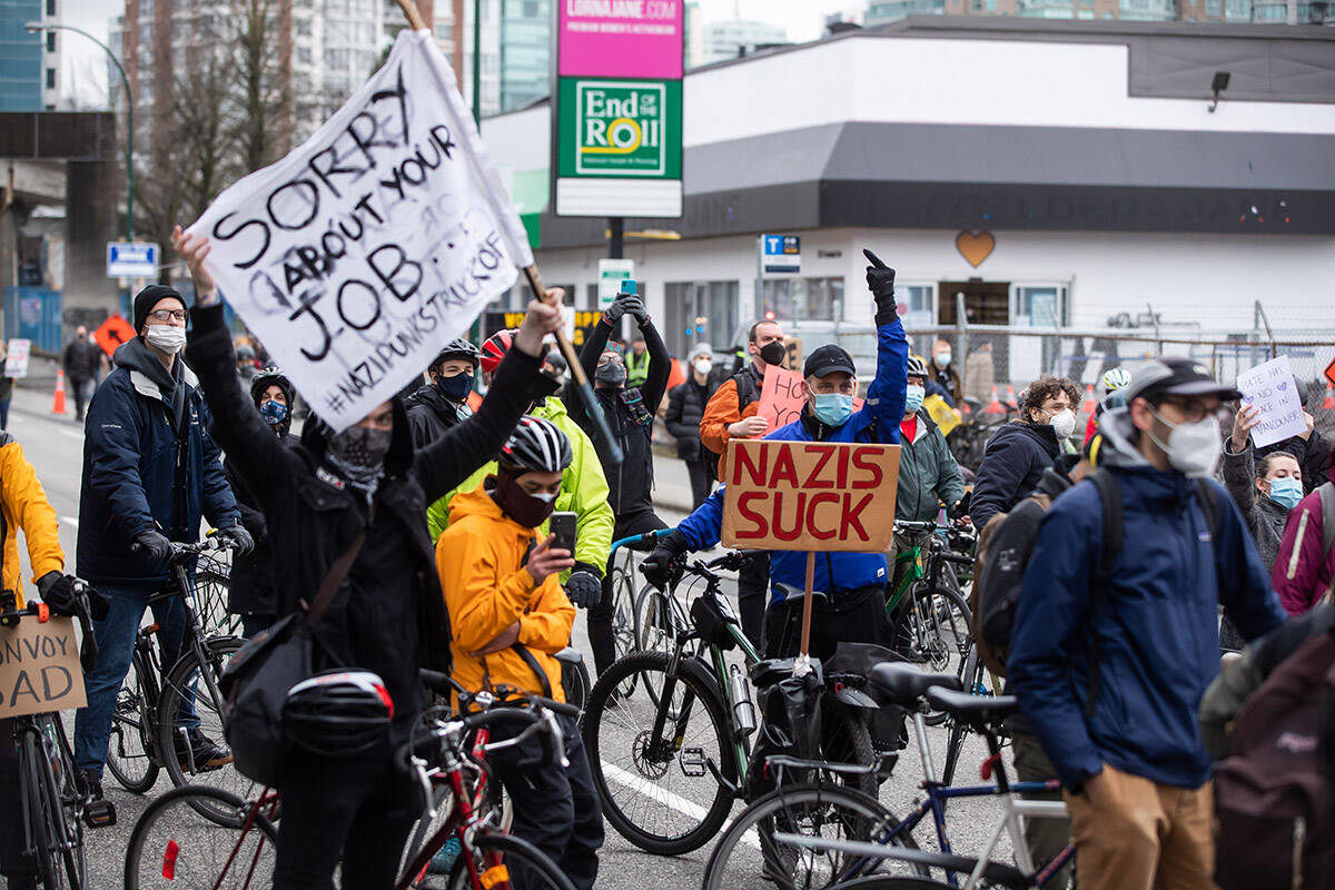 Counter protesters block a convoy of truckers opposed to COVID-19 health measures and vaccinations, in Vancouver, B.C., Saturday, Feb. 5, 2022. A group of more than 200 counter protesters on foot and on bikes held up the convoy for nearly an hour before police officers turned the trucks around and sent them on another route. THE CANADIAN PRESS/Darryl Dyck