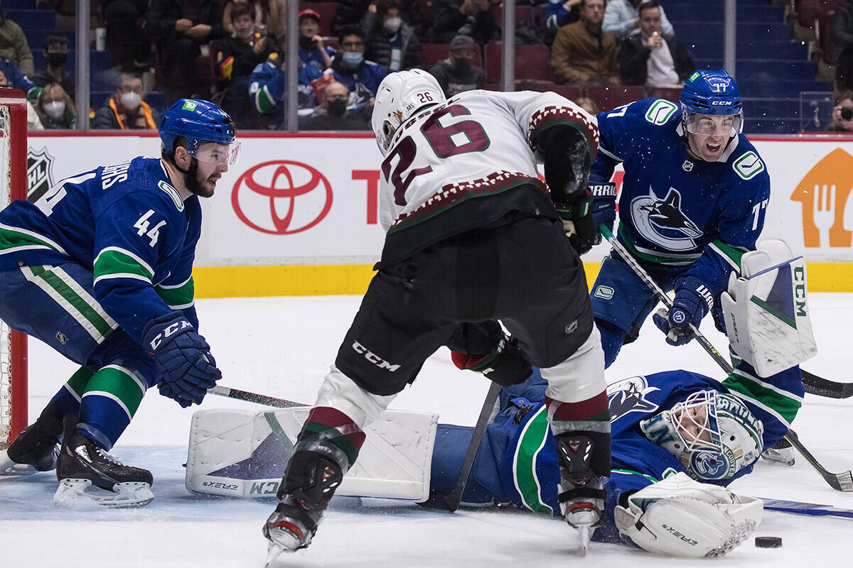 Vancouver Canucks goalie Thatcher Demko, bottom right, stops Arizona Coyotes’ Antoine Roussel (26), of France, as Vancouver’s Kyle Burroughs (44) covers the net during the second period of an NHL hockey game in Vancouver, on Tuesday, February 8, 2022. THE CANADIAN PRESS/Darryl Dyck