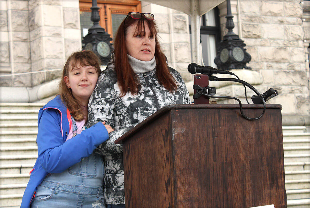 Diane Pearce, right, with her daughter Madison Ross, speaks at a rally Wednesday (Feb. 9) outside the legislature that called on the province to end its planned phase-out of individualized autism funding. (Jake Romphf/News Staff)