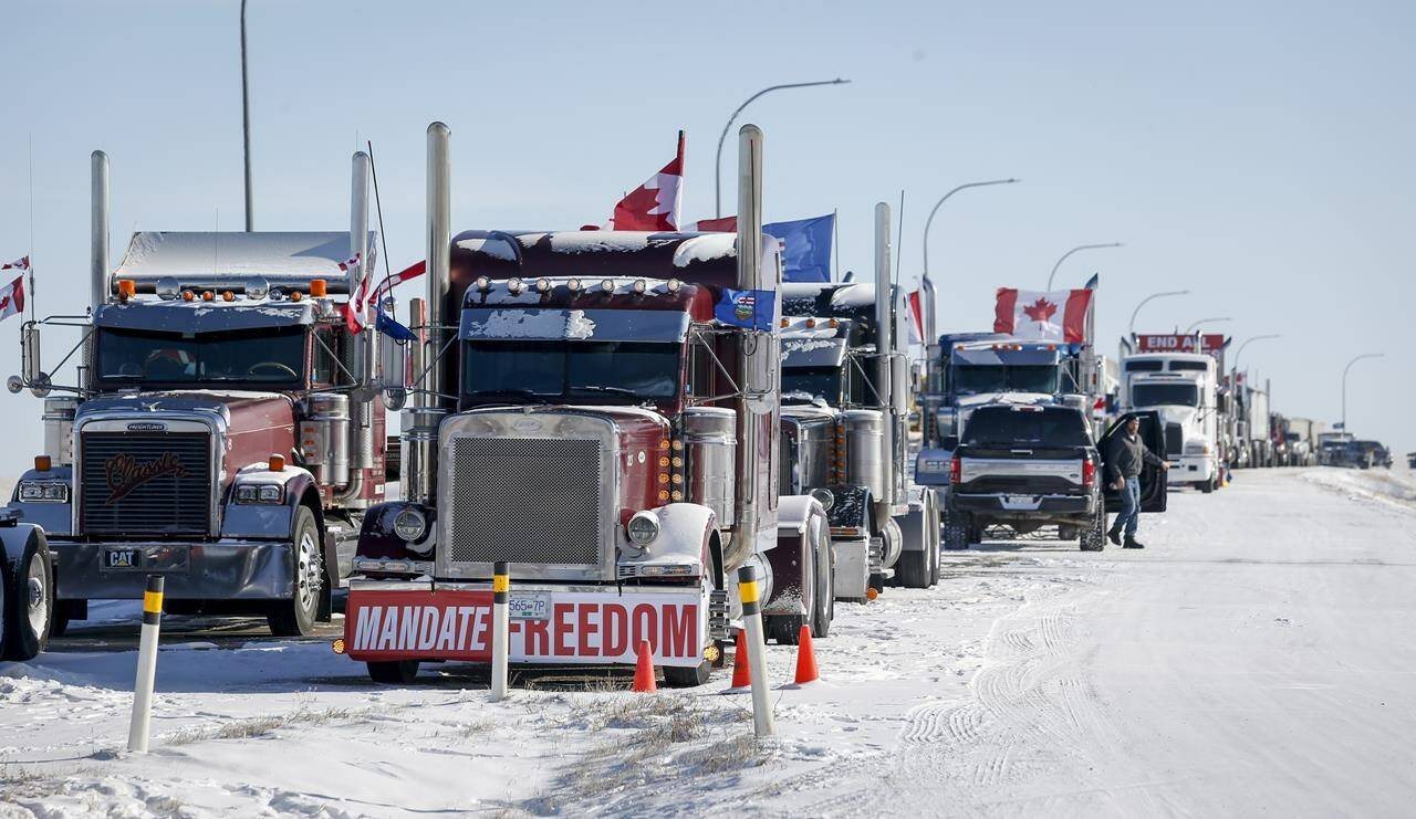 A truck convoy of anti-COVID-19 vaccine mandate demonstrators block the highway at the busy U.S. border crossing in Coutts, Alta., Wednesday, Feb. 2, 2022. THE CANADIAN PRESS/Jeff McIntosh