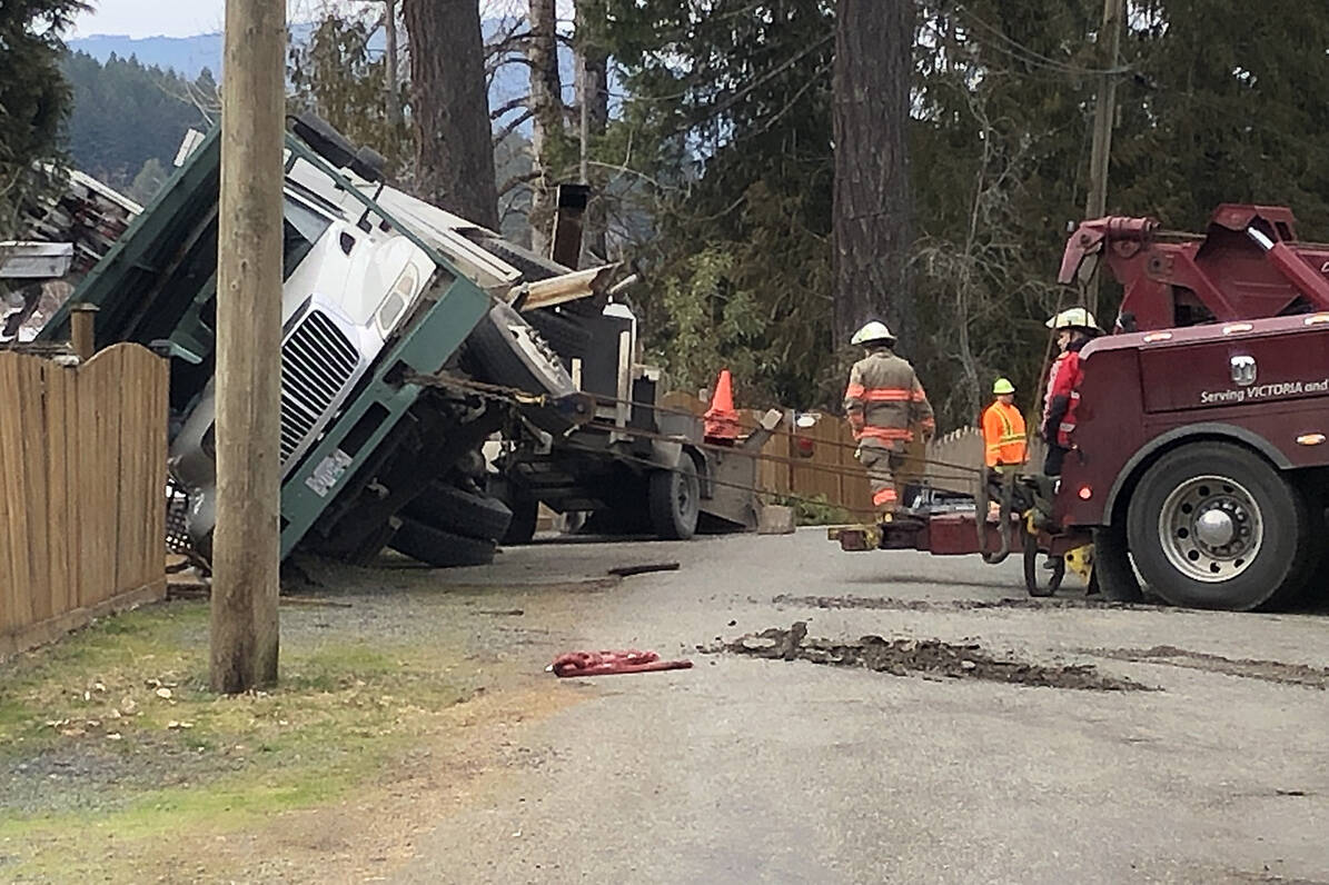 A tow truck pulls a tree trimming truck back to vertical after the trimmer tipped over on Feb. 23, 2022. (Kevin Rothbauer/Citizen)