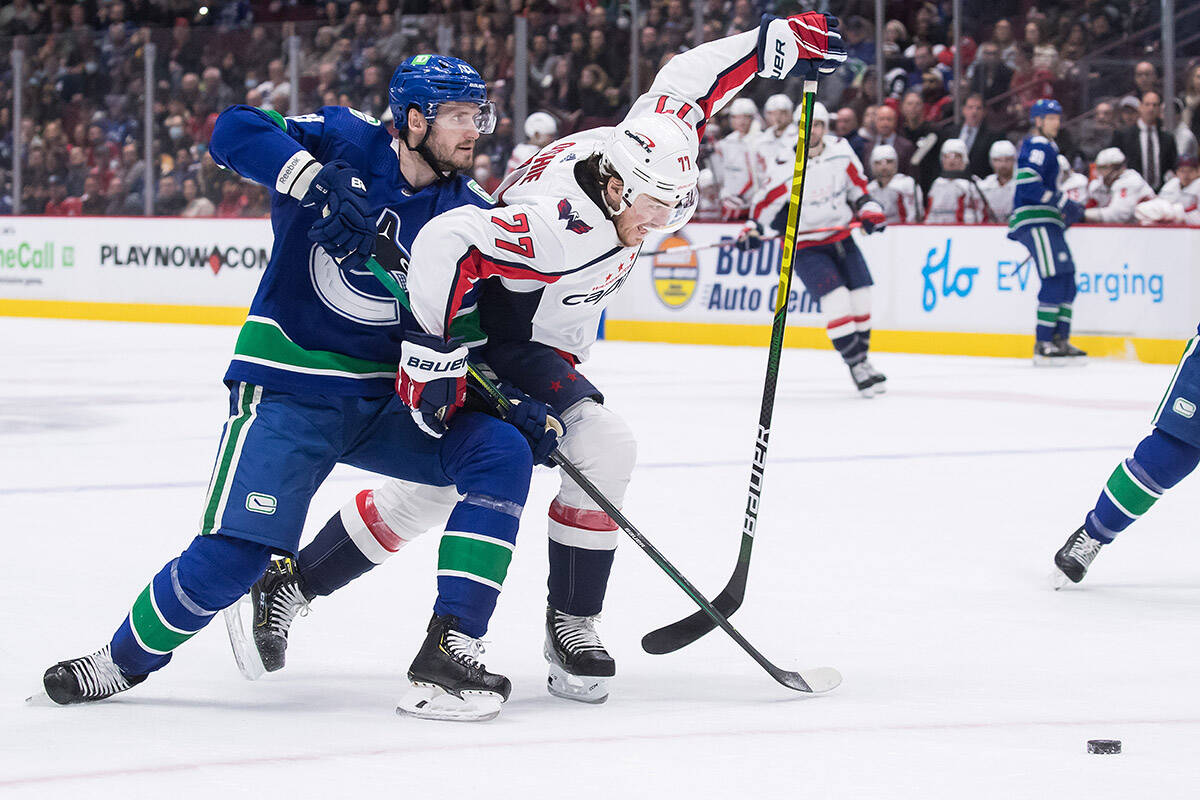 Vancouver Canucks’ Oliver Ekman-Larsson, left, of Sweden, checks Washington Capitals’ T.J. Oshie during the first period of an NHL hockey game in Vancouver, on Friday, March 11, 2022. THE CANADIAN PRESS/Darryl Dyck