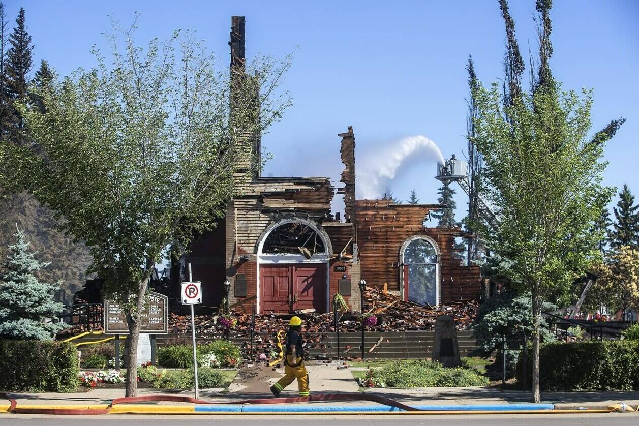 St. Jean Baptiste Parish Catholic church is shown in Morinville Alta, on Wednesday June 30, 2021 as firefighters put out hot spots. Alberta is more than doubling the amount of funding for a program it announced last summer for security improvements at religious facilities to protect them from hate crimes and vandalism. THE CANADIAN PRESS/Jason Franson
