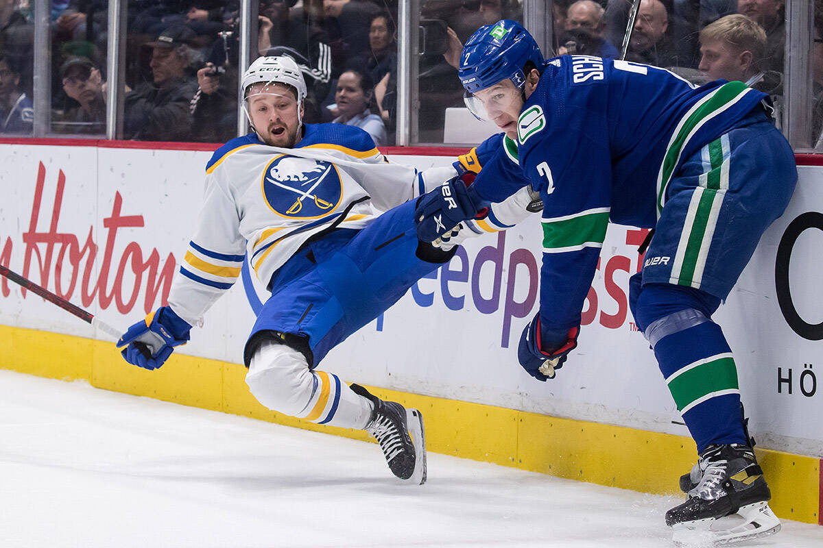 Vancouver Canucks’ Luke Schenn, right, checks Buffalo Sabres’ Rasmus Asplund, of Sweden, during the first period of an NHL hockey game in Vancouver, B.C., Sunday, March 20, 2022. THE CANADIAN PRESS/Darryl Dyck