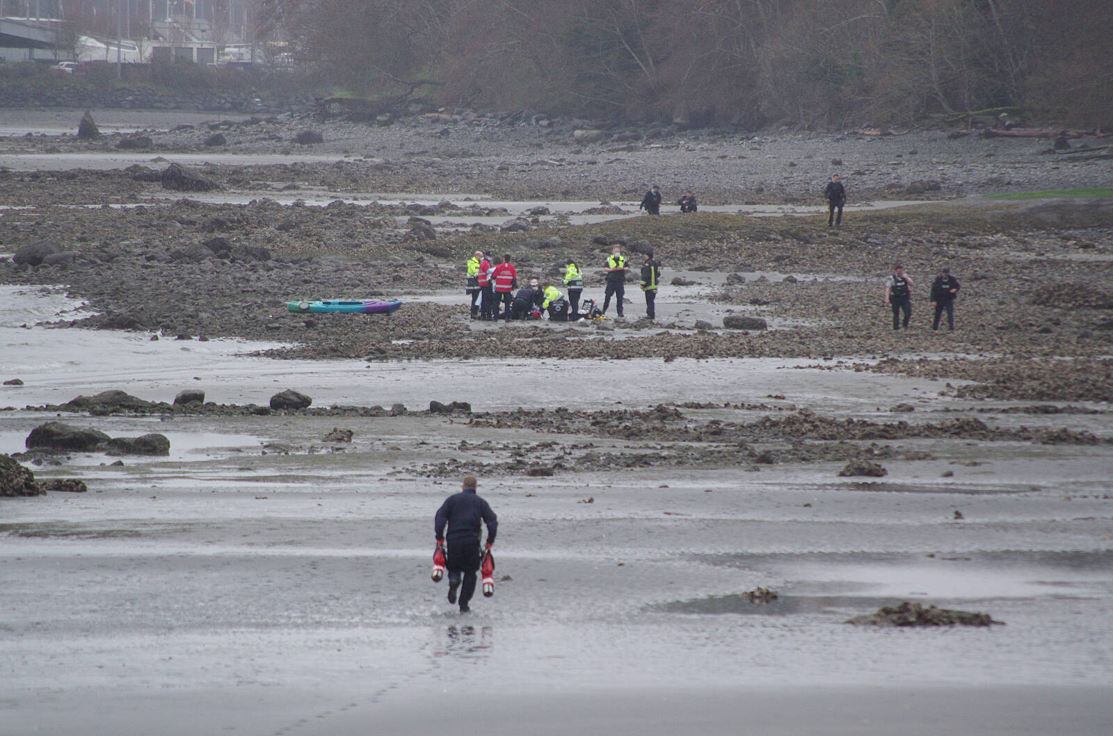 A Nanaimo firefighter runs with tanks of oxygen to where emergency crews are working to save the life of a man who was found in the waters of Departure Bay on Monday, March 21. (Chris Bush/News Bulletin)