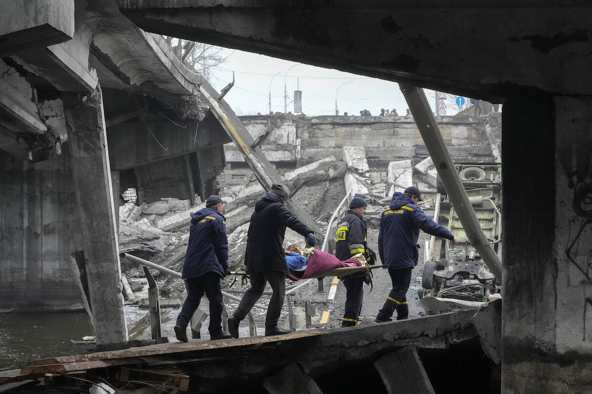 Ukrainian rescue workers carry an elderly woman under a destroyed bridge in Irpin, close to Kyiv, Ukraine, Friday, April 1, 2022. Talks to stop the fighting in Ukraine resumed Friday, as another attempt to rescue civilians from the shattered and encircled city of Mariupol broke down and Russia accused the Ukrainians of a cross-border helicopter attack on an oil depot. (AP Photo/Efrem Lukatsky)