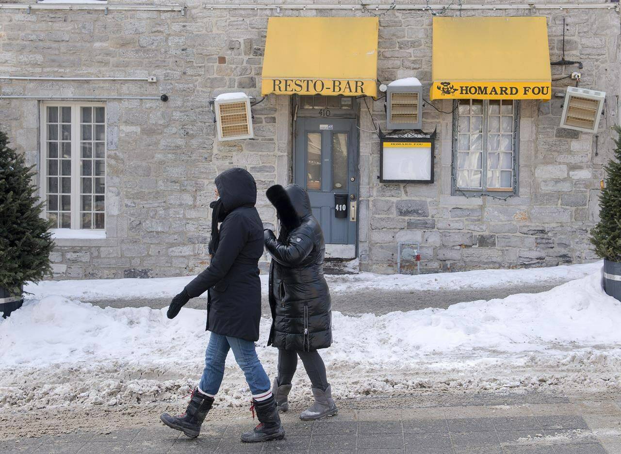People walk by a Resto-Bar in Old Montreal, Monday, January 31, 2022, as the COVID-19 pandemic continues in Canada. Businesses across Canada are struggling to cope with the sixth wave of COVID-19, as staffing shortages hamper sectors from health care to retail and restaurants.THE CANADIAN PRESS/Graham Hughes