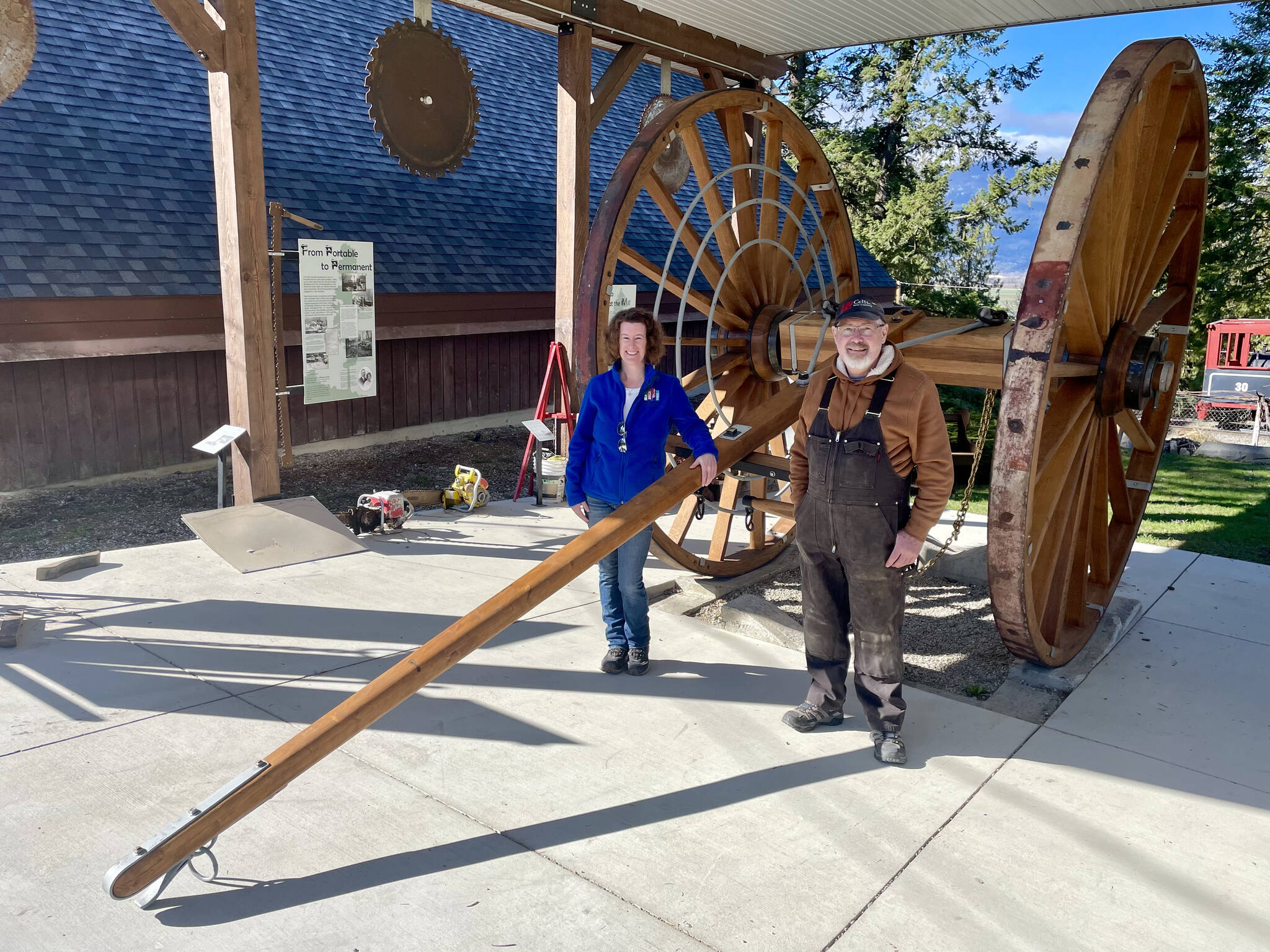 Museum manager Tammy Bradford and wheelwright Brian Reynolds pose in front of restored logging arch. (Photo by Kelsey Yates)