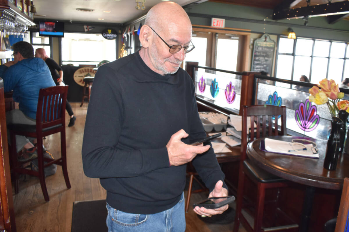 Bill Singer checks for proof of vaccination at the doors of the Rumrunner Pub, which he owns and manages in Sidney. His decision to keep the vaccination requirement in place has sparked online criticism but also earned praise from customers. (Wolf Depner/News Staff)