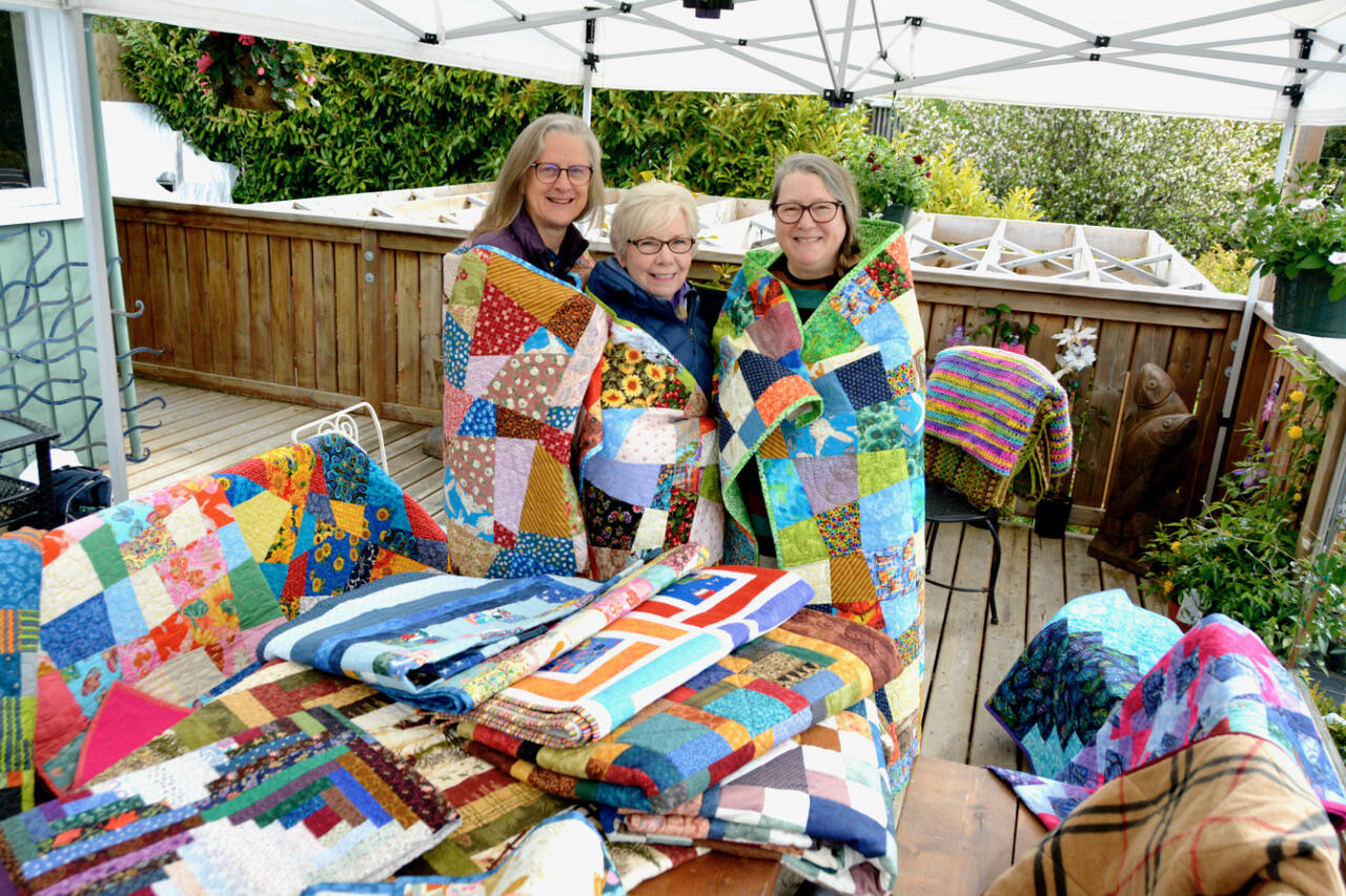 Bridget Ducker (left), Dolores Dowler and Mary-Ann Tennent with a collection of quilts. (Kevin Laird - Black Press Media)