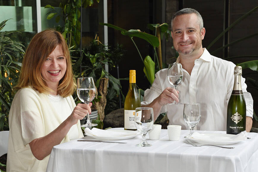 Karin Kallio from Mark Anthony Wine and Spirits, and Aidan Henry of Brink Events raise a glass to toast the return of the annual pop-up all-white picnic and dance party Diner en Blanc, which returns June 23. (Don Denton/Black Press Media)