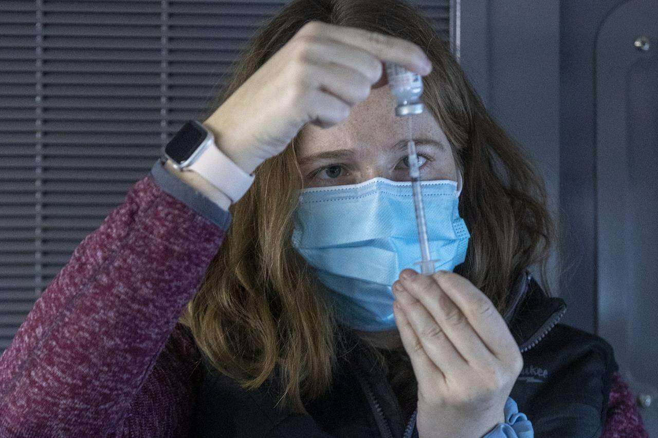 A doctor draws out vaccine during a drive-through COVID-19 vaccine clinic at St. Lawrence College in Kingston, Ont., on Sunday, Jan. 2, 2022. THE CANADIAN PRESS/Lars Hagberg