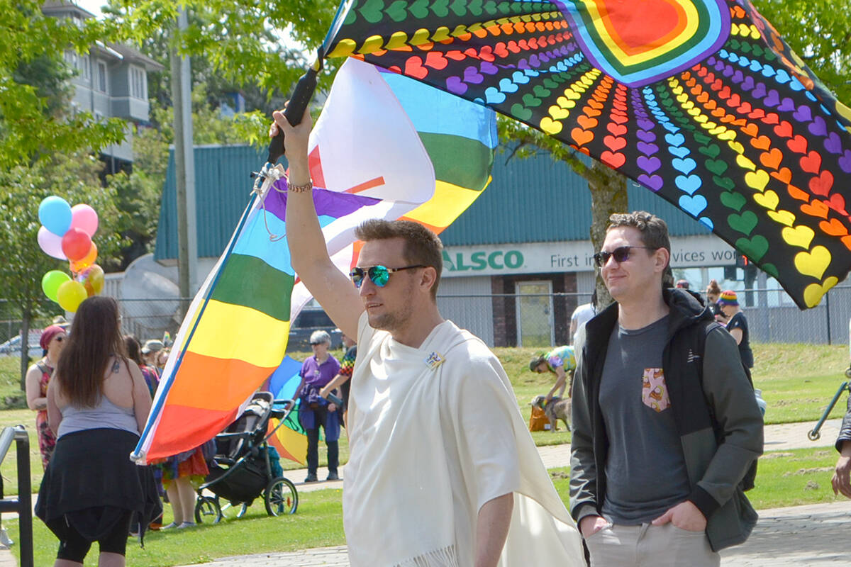 Tyler Green marches into Nanaimo’s Maffeo Sutton Park twirling an LGBTQ rainbow love heart flag and a Canadian rainbow flag on June 12 for the Nanaimo Pride Society’s Pride Festival. (Mandy Moraes/News Bulletin)