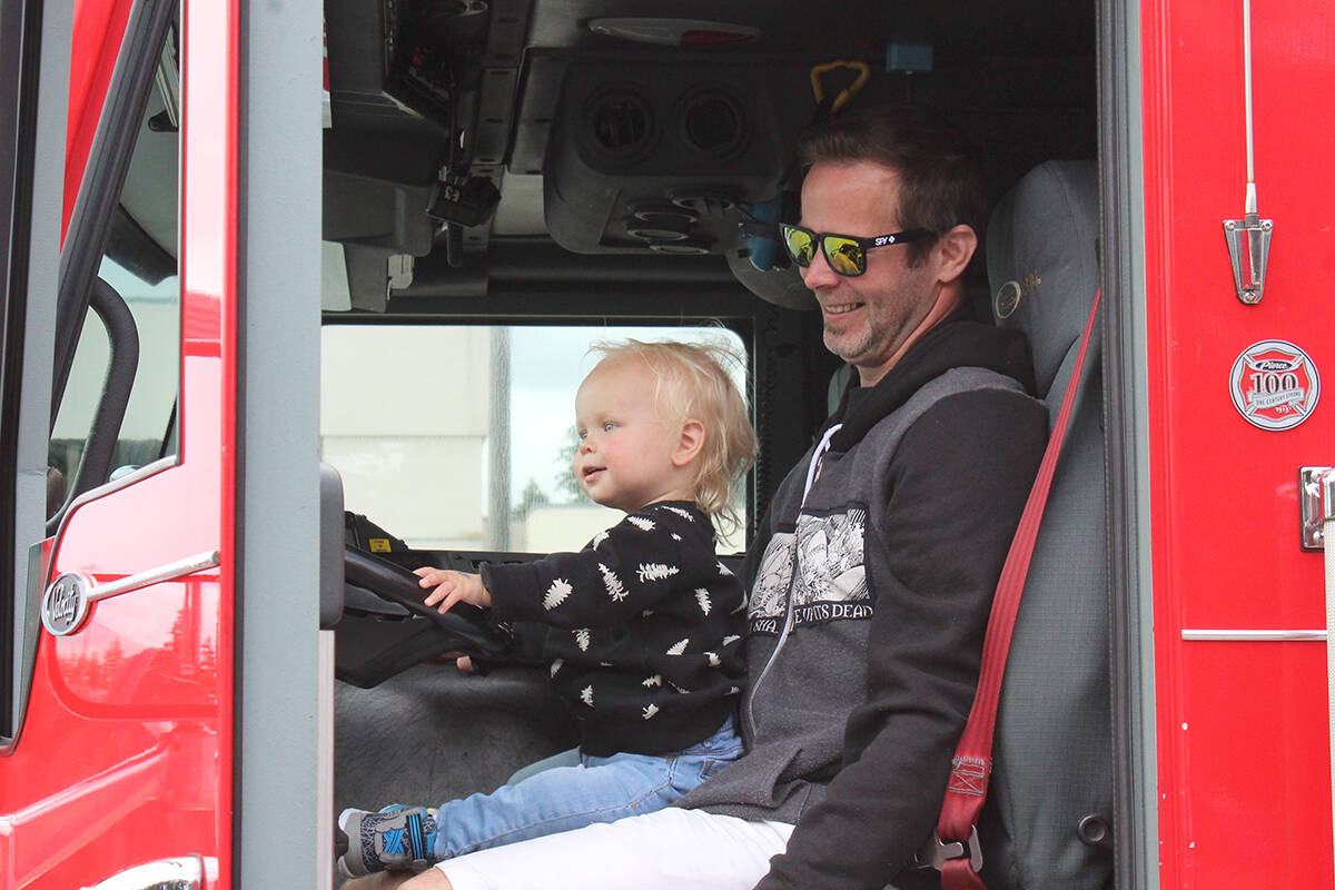 One-and-a-half-year-old Bowie Wardle and Leif Wardle climb into the driver’s seat of a Nanaimo Fire Rescue truck Sunday, June 19, at Touch A Truck at the Woodgrove Centre parking lot. (Greg Sakaki/News Bulletin)