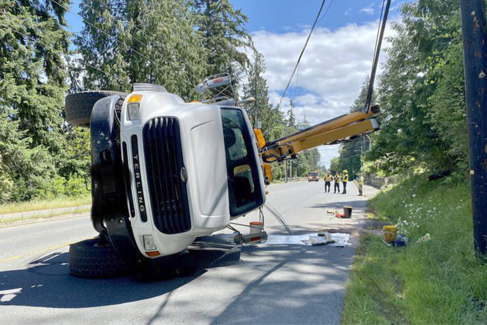 A section of Hammond Bay Road was closed for several hours Wednesday, June 22, after a crane truck became entangled in communication lines and rolled on its side. There were no injuries reported. (Photo: Nanaimo Fire Rescue)