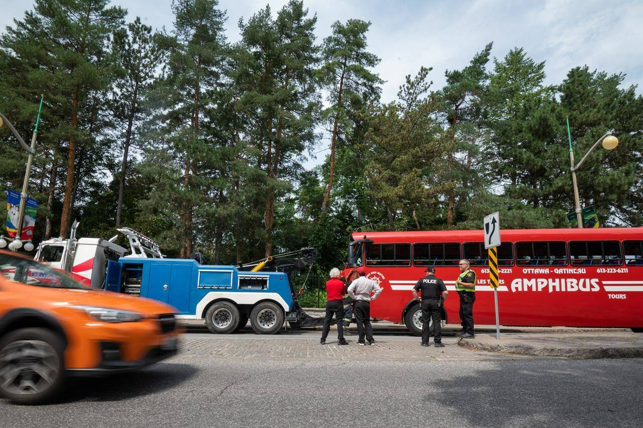 An Ottawa Police Service (OPS) office, Ministry of Transportation (MTO) officer and employees from Lady Dive Tour look at the aftermath of a single-vehicle accident involving an amphibious Lady Dive Tour vehicle which crashed into the 24 Sussex Dr. in Ottawa, Ont. on Wednesday, Aug. 3, 2022. THE CANADIAN PRESS/Spencer Colby