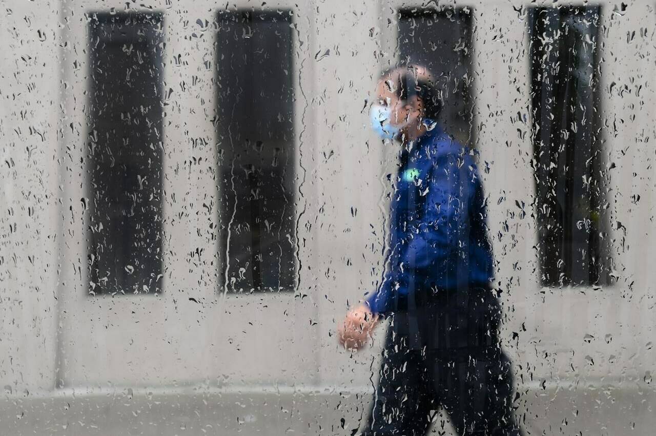 FILE – A pedestrian walks alongside businesses on a rainy day while wearing a protective mask during the COVID-19 pandemic in Toronto on June 18, 2021. A new Statistics Canada study has found that some racialized populations in Canada had significantly higher mortality rates from COVID-19. THE CANADIAN PRESS/Nathan Denette