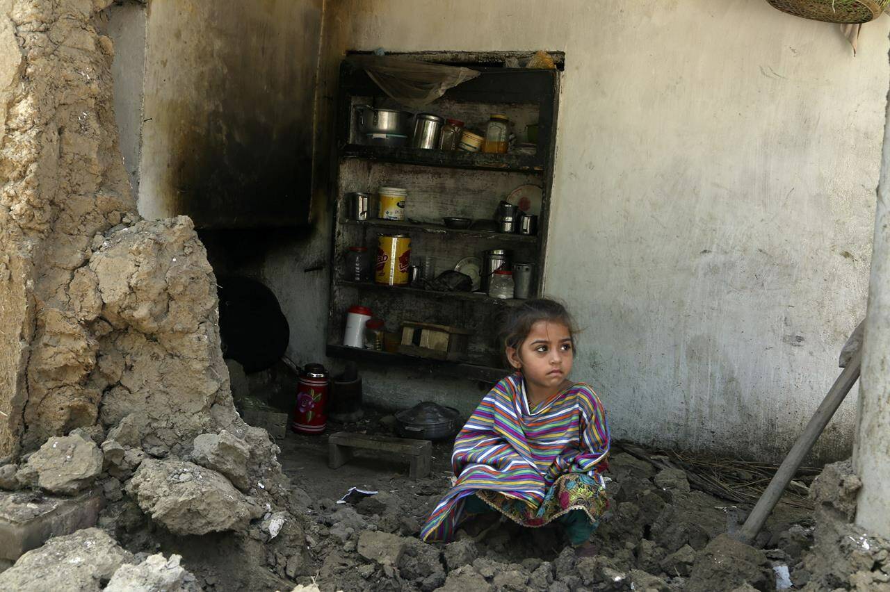 A girl sits amid the rubble of her damaged home after heavy rains in Charsadda, Pakistan, Tuesday, Aug. 30, 2022. The United Nations and Pakistan have appealed for $160 million in emergency funds for nearly a half million displaced victims of record-breaking floods that have killed more than 1,150 people since mid-June. (AP Photo/Mohammad Sajjad)