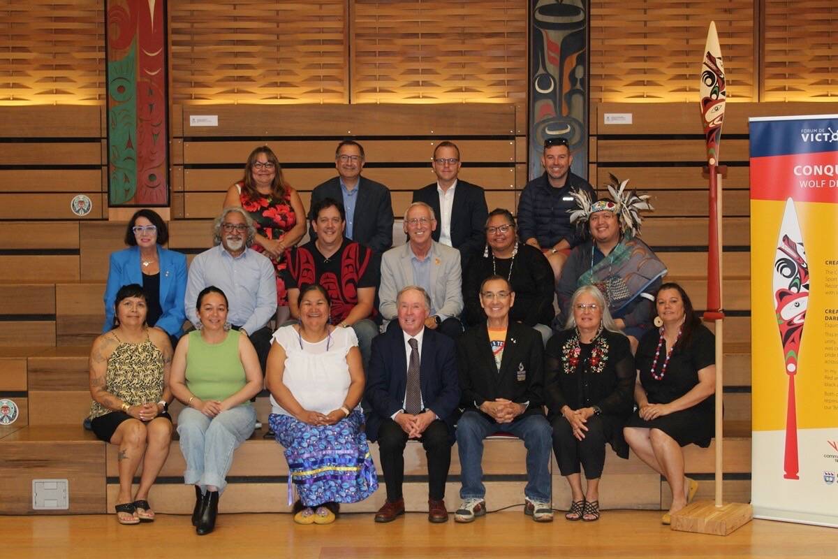 Indigenous community members, international delegates and Victoria Forum organizers sit for a photo next to a hand-carved paddle, designed by Darlene Gait of Esquimalt (Xwsepsum) Nation, inside the University of Victoria’s First Peoples House. (Austin Westphal/News Staff)