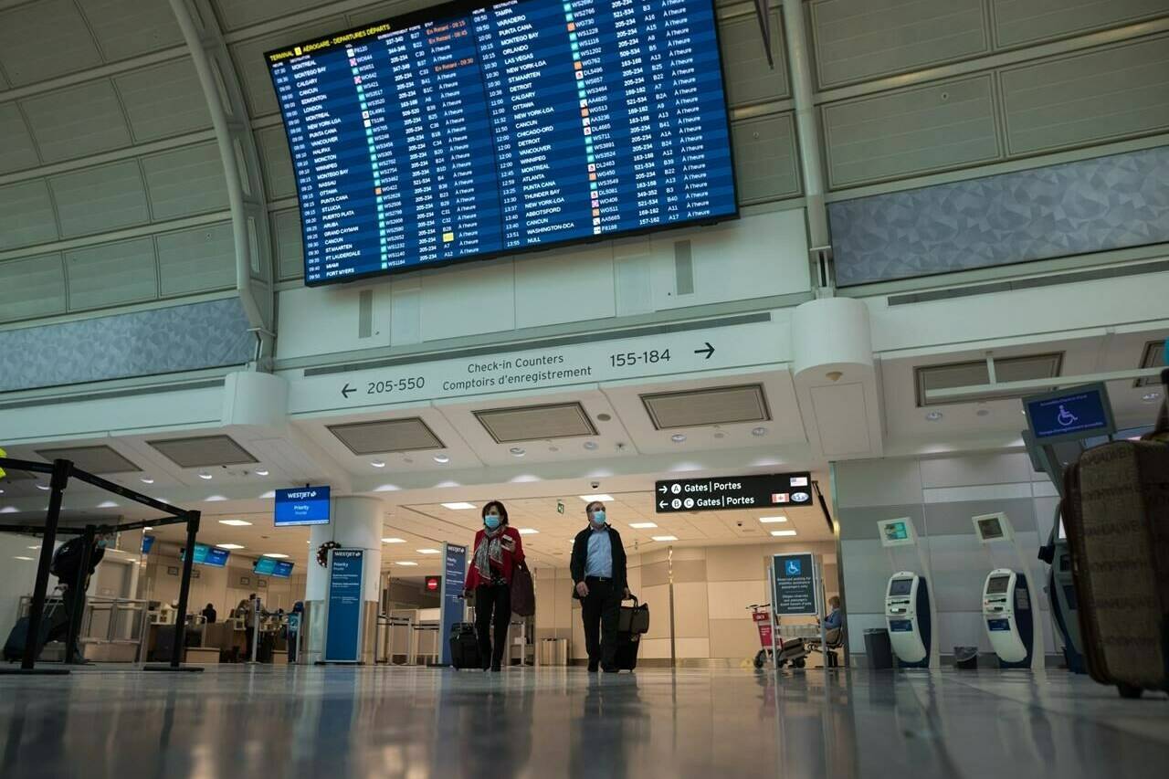 Travelers are photographed at Toronto Pearson International Airport, on Thursday, December 16, 2021. New Air Passenger Protection Regulations go into effect this week. THE CANADIAN PRESS/Tijana Martin