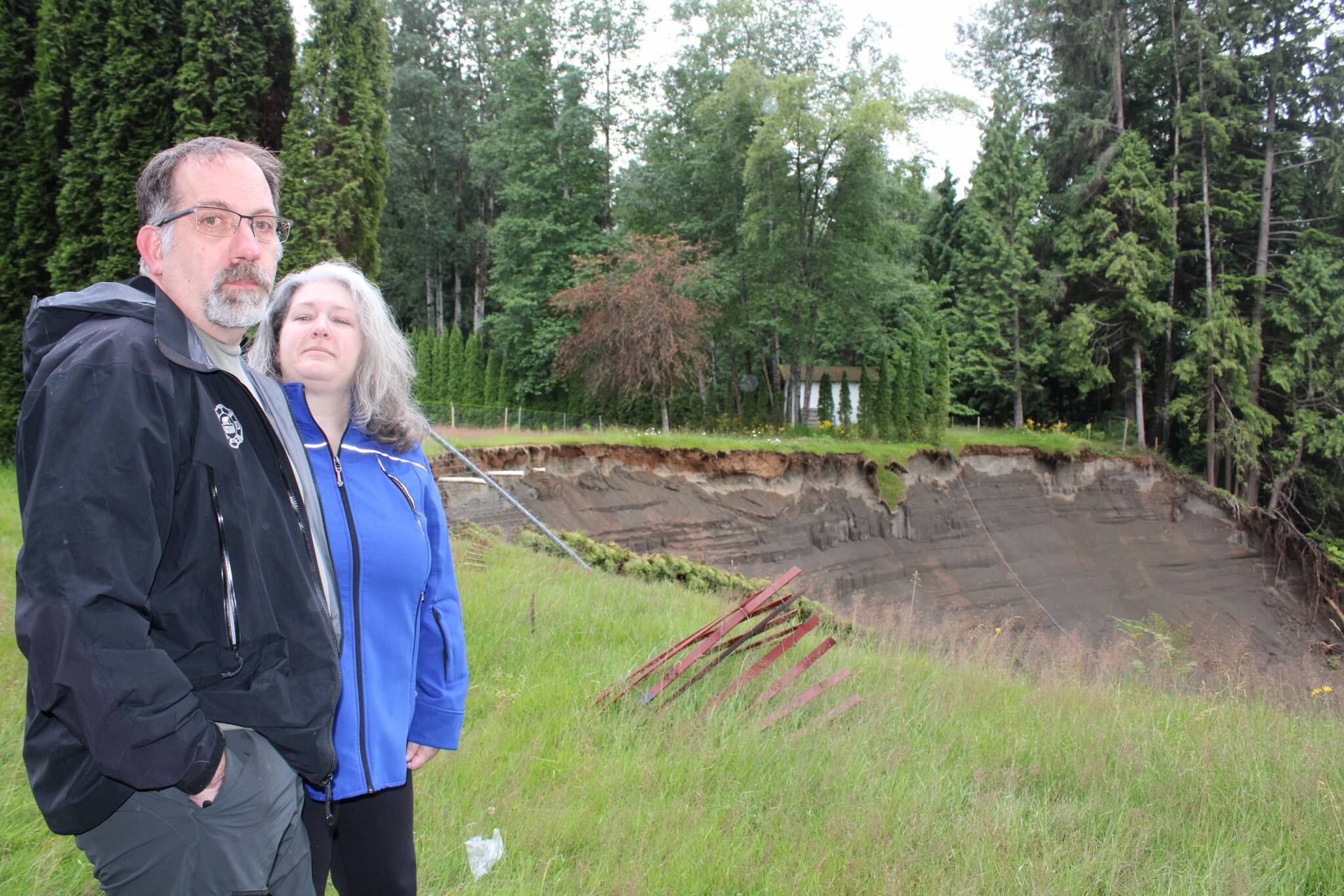 David and Amanda Horvath look over the looming cliff of a landslide behind their home at 5412 McConnell Crescent in Terrace, B.C. (Michael Bramadat-Willcock/Terrace Standard)