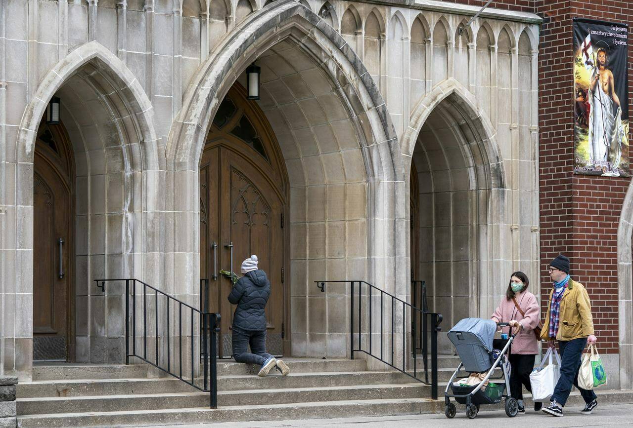 A woman prays on the steps outside St. Casimir Church in Toronto on Friday May 1, 2020. THE CANADIAN PRESS/Frank Gunn