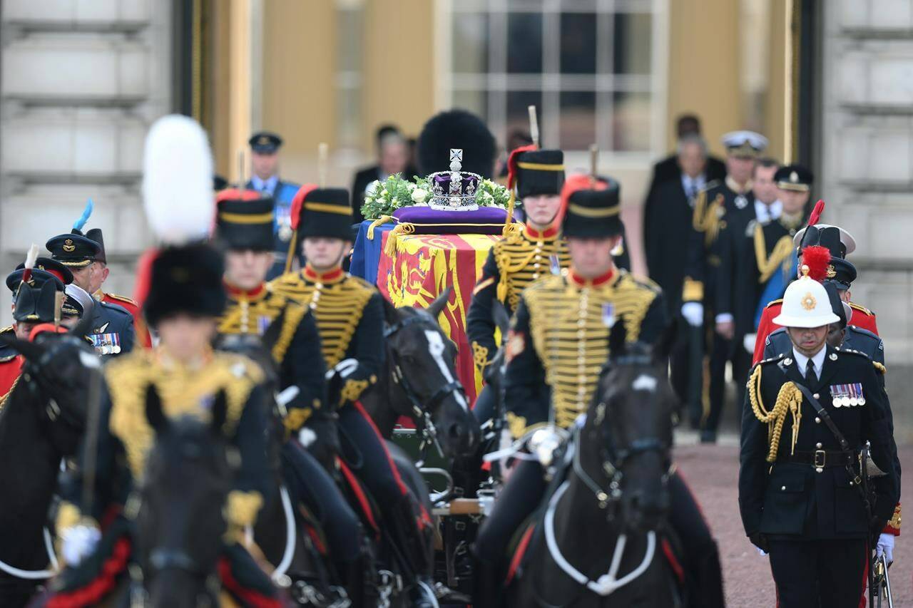 A view of the coffin of Queen Elizabeth II, adorned with a Royal Standard and the Imperial State Crown and pulled by a Gun Carriage of The King’s Troop Royal Horse Artillery, during a procession from Buckingham Palace to Westminster Hall in London, Wednesday, Sept. 14, 2022. The Queen will lie in state in Westminster Hall for four full days before her funeral on Monday Sept. 19. (Daniel Leal/Pool Photo via AP)