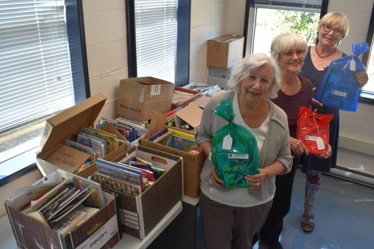 Nancy Dobbs, Paulette Kushner and Daphne Macnaughton of the Peninsula 1000 x 5 Children’s Book Recycling Project hold up bags of books ready to go out to children aged birth to five. (Wolf Depner/News Staff)