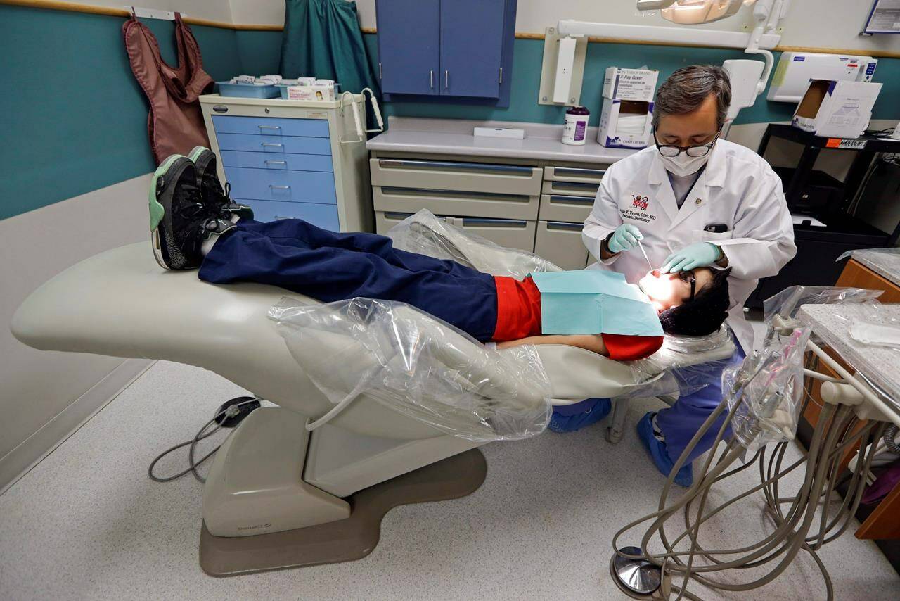 A dentist at the Riley Hospital for Children Department of Pediatric Dentistry, checks the teeth of Justin Perez, 11, during an office visit in Indianapolis, Friday, Jan. 22, 2016. University of Calgary associate economics professor Lindsay Tedds warns the federal dental benefit for children opens families up to the potential for “clawbacks” if they don’t spend all the money on their kids’ teeth.THE CANADIAN PRESS/AP-Michael Conroy