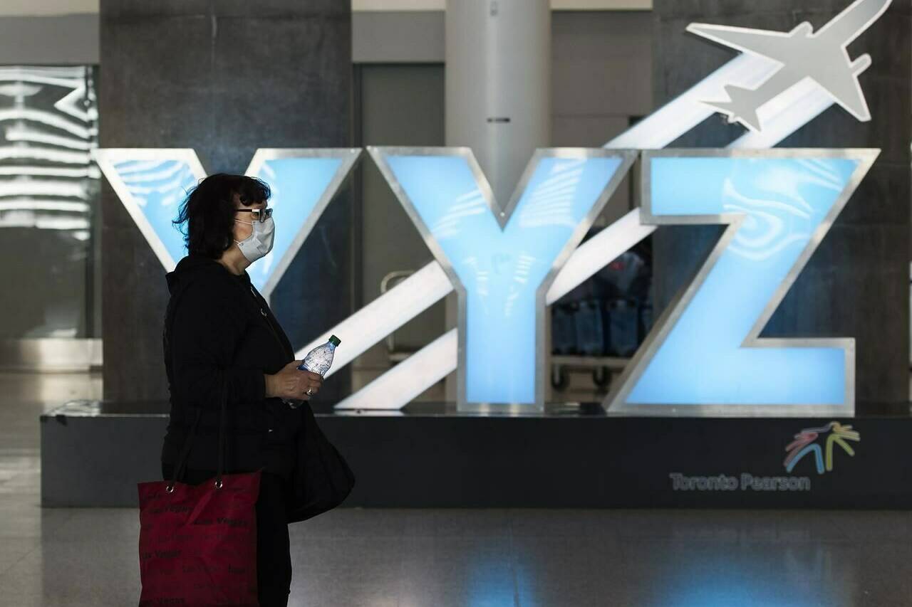 A woman walks through Pearson International Airport in Toronto on March 16, 2020. As of Saturday, October 1, 2022, travellers to Canada will no longer be required to show proof of vaccination against COVID-19 — and wearing a mask on planes and trains is no longer mandatory, though it is still recommended. THE CANADIAN PRESS/Nathan Denette