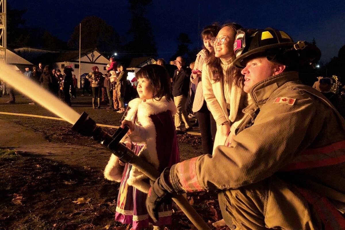 Children line up to help Oak Bay firefighter Cody Brown manage a large Halloween bonfire at Fireman’s Park in 2018. (Black Press Media file photo)