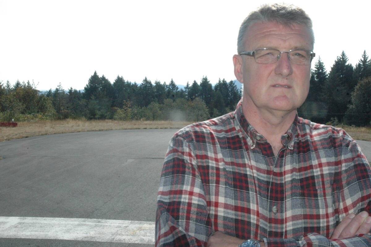 The Duncan Flying Club's Kevin Maher stands in front of tall trees at the end of the runway at Duncan Airport that are impeding air traffic at the facility. (Robert Barron/Citizen)