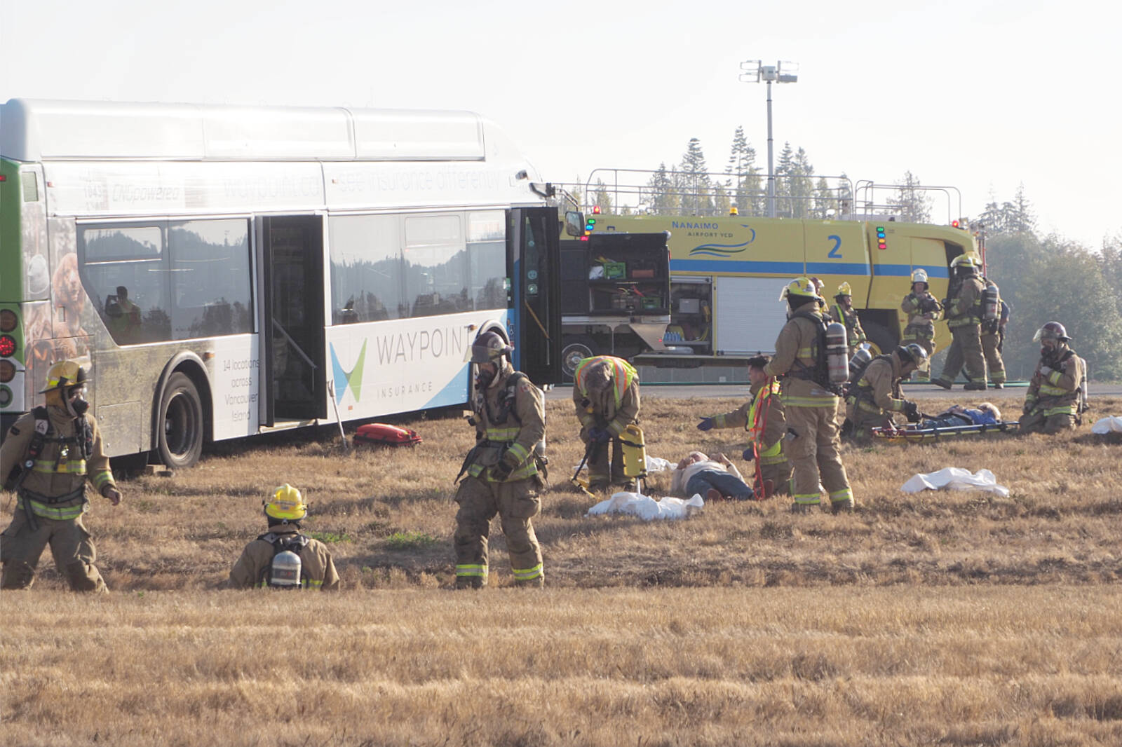 Airport, North Cedar and Cranberry firefighters move ‘crash victims’ from the field around a RDN Transit bus standing in for a stricken aircraft during an emergency preparedness exercise at Nanaimo Airport on Wednesday, Oct. 19. (Chris Bush/News Bulletin)