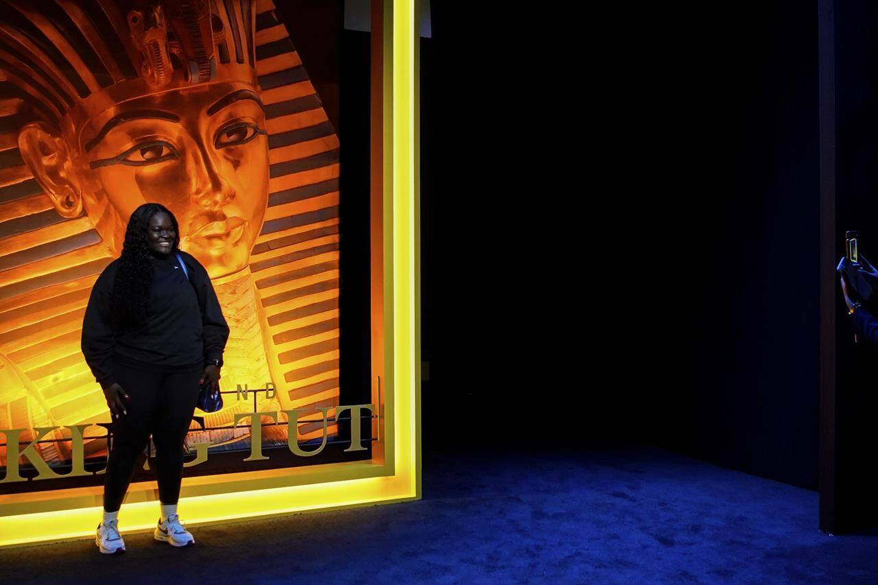 A person poses for a photo in front a large replica of National Geographic’s Sept. 2010 magazine cover at the Beyond King Tut Immersive Experience, Thursday, Oct. 27, 2022, in New York. The exhibition will open to the public on Friday, in commemoration of the the 100th anniversary of the discovery of King Tut’s tomb on Nov. 4, 1922. (AP Photo/Julia Nikhinson)