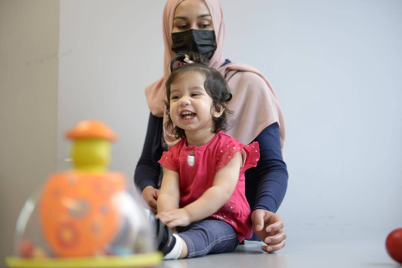In this photo provided by the Children’s Hospital of Eastern Ontario, Ayla Bashir sits with her mother, Sobia Qureshi, during a physical therapy assessment for Ayla at CHEO in Ottawa on Aug. 23, 2022. The toddler is the first child treated as fetus for Pompe disease, an inherited and fatal disorder in which the body fails to make some or all of a crucial protein. (André Coutu/CHEO via AP)
