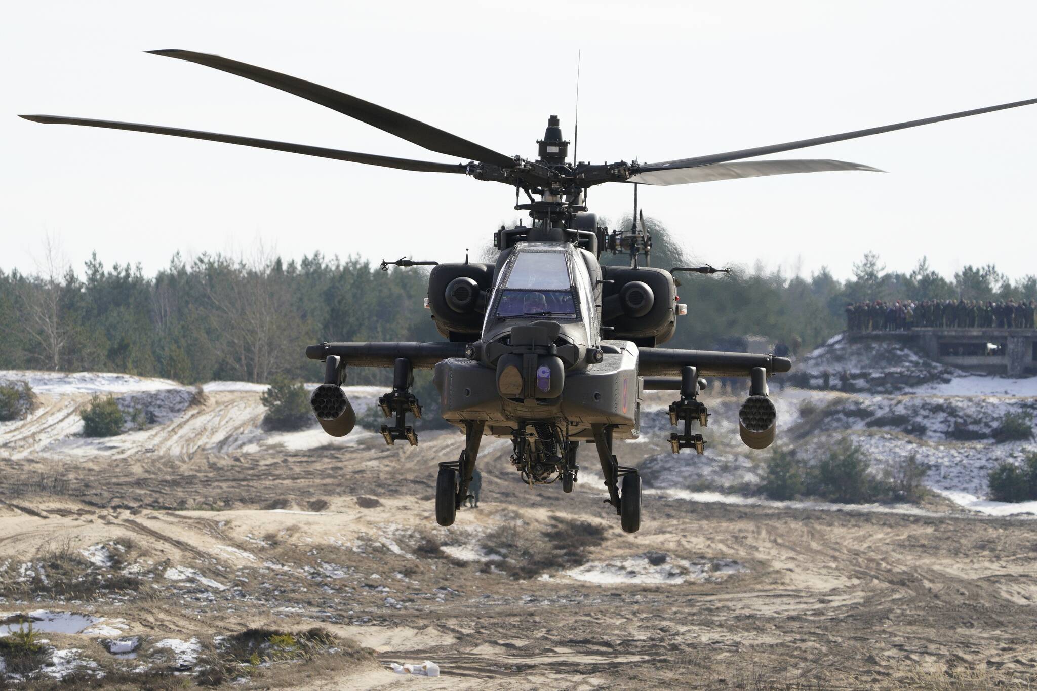 A U.S. Boeing AH-64 Apache attack helicopter flies during the NATO military exercises Crystal arrow 2022 at the Adazi military range, Latvia, Friday, March 11, 2022. About 2,800 soldiers from Albania, Canada, Czech Republic, Italy, Iceland, Montenegro, Poland, Slovakia, Slovenia, Spain, Latvia and the United States attend the training for interoperability during tactical military operations, including the demonstration of winter capability. (Martins Zilgalvis/F64 via AP)