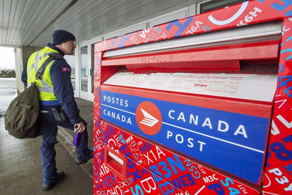 A Canada Post worker and mail box. (File photo: THE CANADIAN PRESS/Ryan Remiorz)