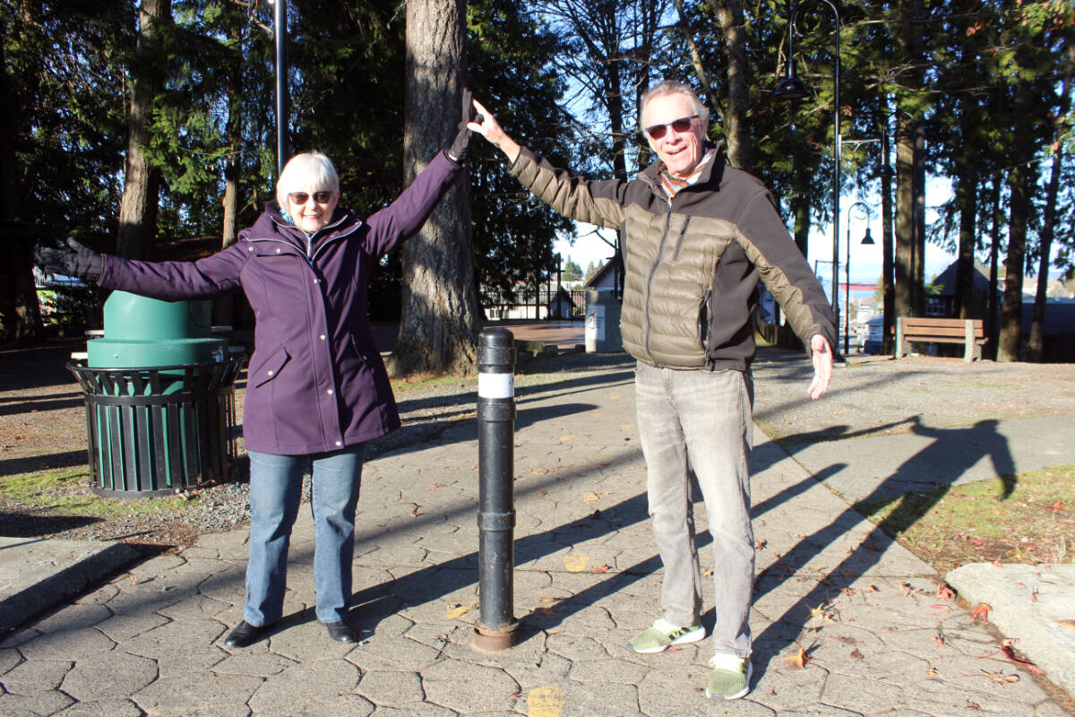 Shannon Bellamy and Tom Andrews of the Chemainus Festival of Murals Society form their own arch with help from their shadowy friends at the site in Waterwheel Park where a new welcome arch will go up by next fall. (Photo by Don Bodger)